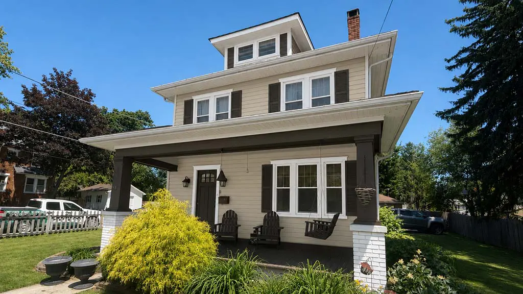 exterior view of a two story craftsman style home with freshly painted beige siding white trim and dark brown shutters