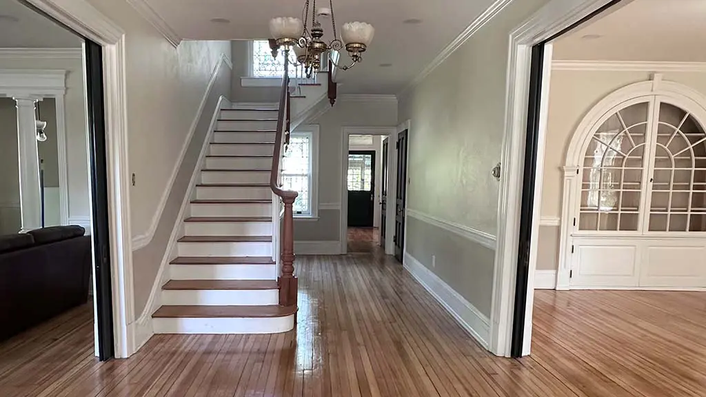 spacious home entryway featuring painted neutral walls bright white trim and refinished hardwood flooring
